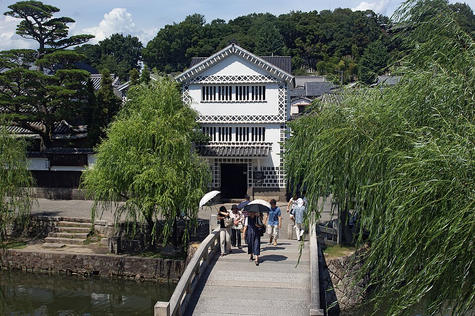 倉敷美観地区の白壁の建物と柳、石橋を渡る人たち