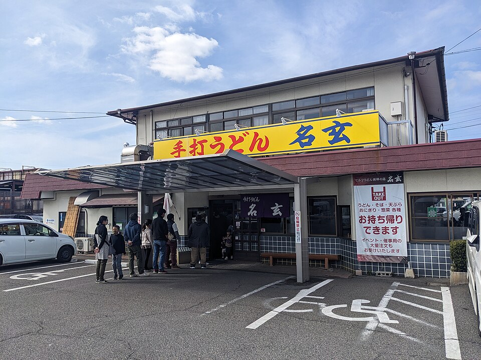黄色い「手打うどん 名玄」の看板と庇がある平井の店舗入口。2023年2月撮影。