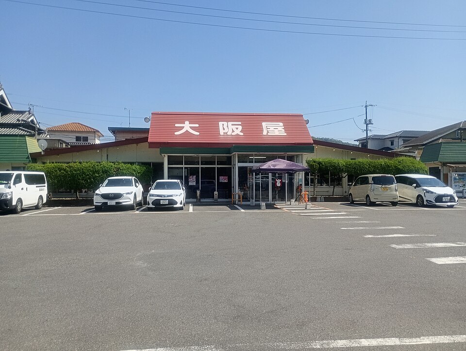 青空の下、赤い屋根に大阪屋と書かれた店舗正面。2026年7月撮影。