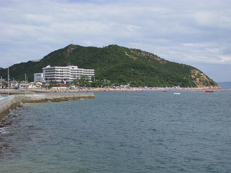 渋川海岸の海と砂浜、海岸沿いの建物と山
