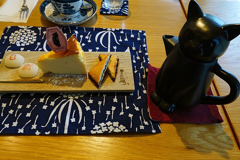 木のトレーに並ぶスイーツと黒猫の形のティーポット