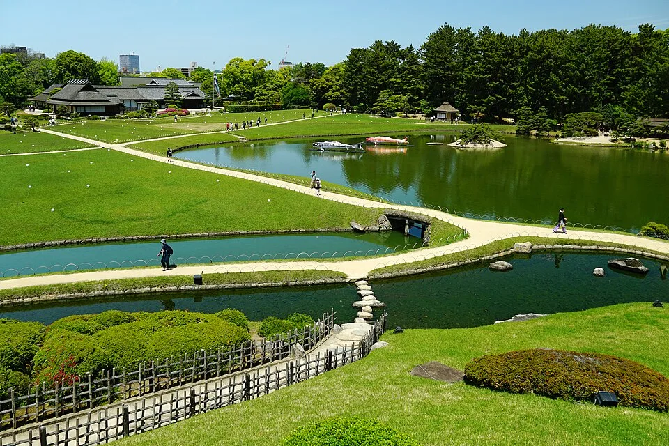 後楽園の池と芝生、その周りを歩く人たち
