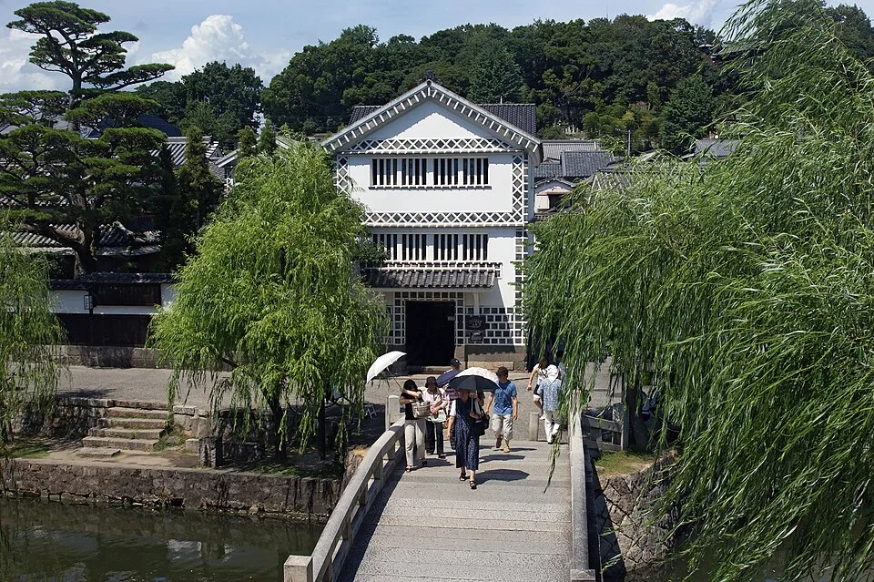 倉敷美観地区の白壁の建物と柳、石橋を渡る人たち