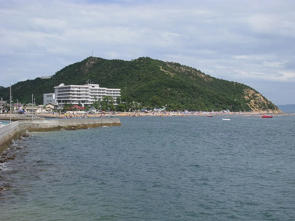 渋川海岸の海と砂浜、海岸沿いの建物と山
