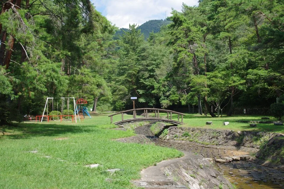 砂川公園の小川と橋、その横のブランコなどの遊具(2017年)